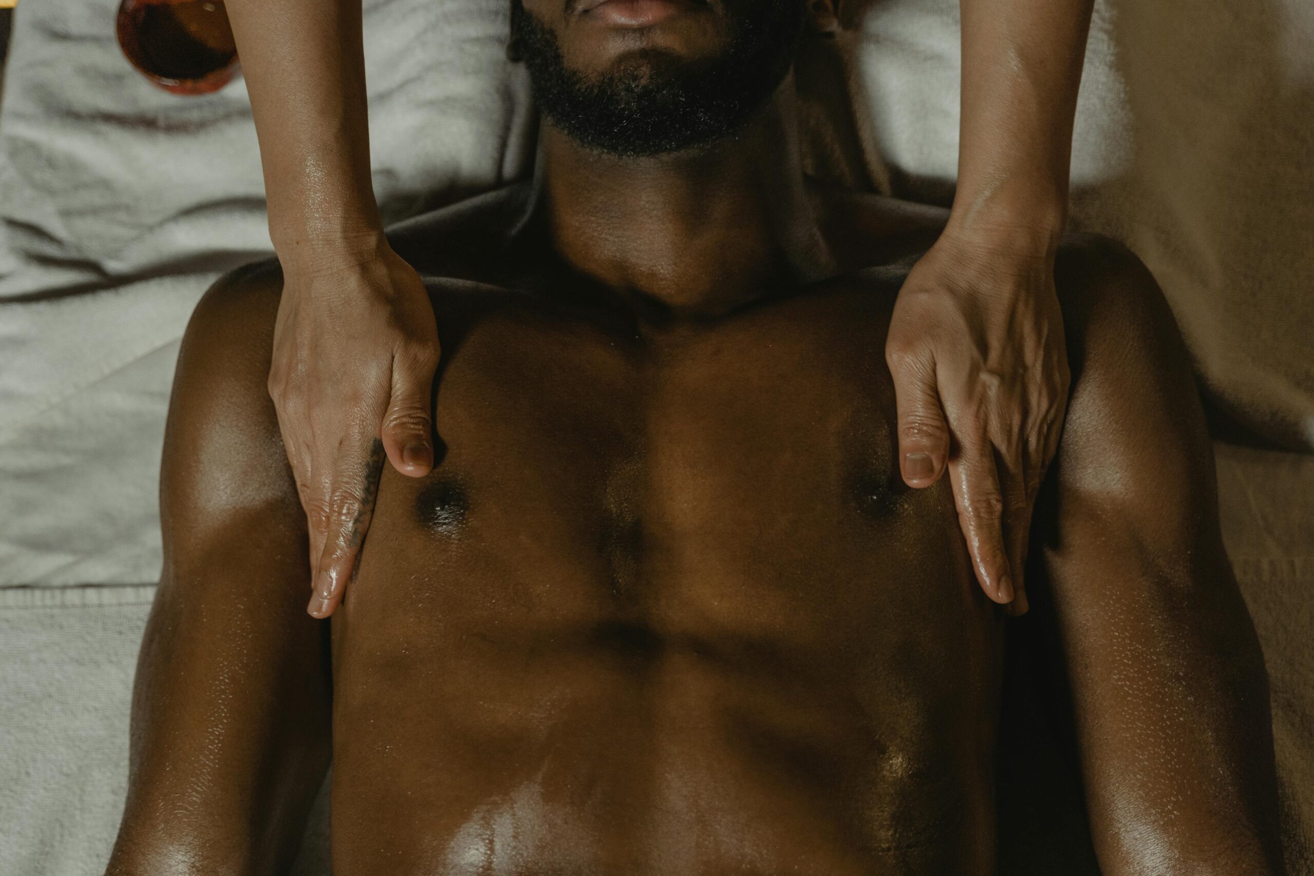 Huile de massage érotique bienfaits - mains pratiquant un massage sensuel